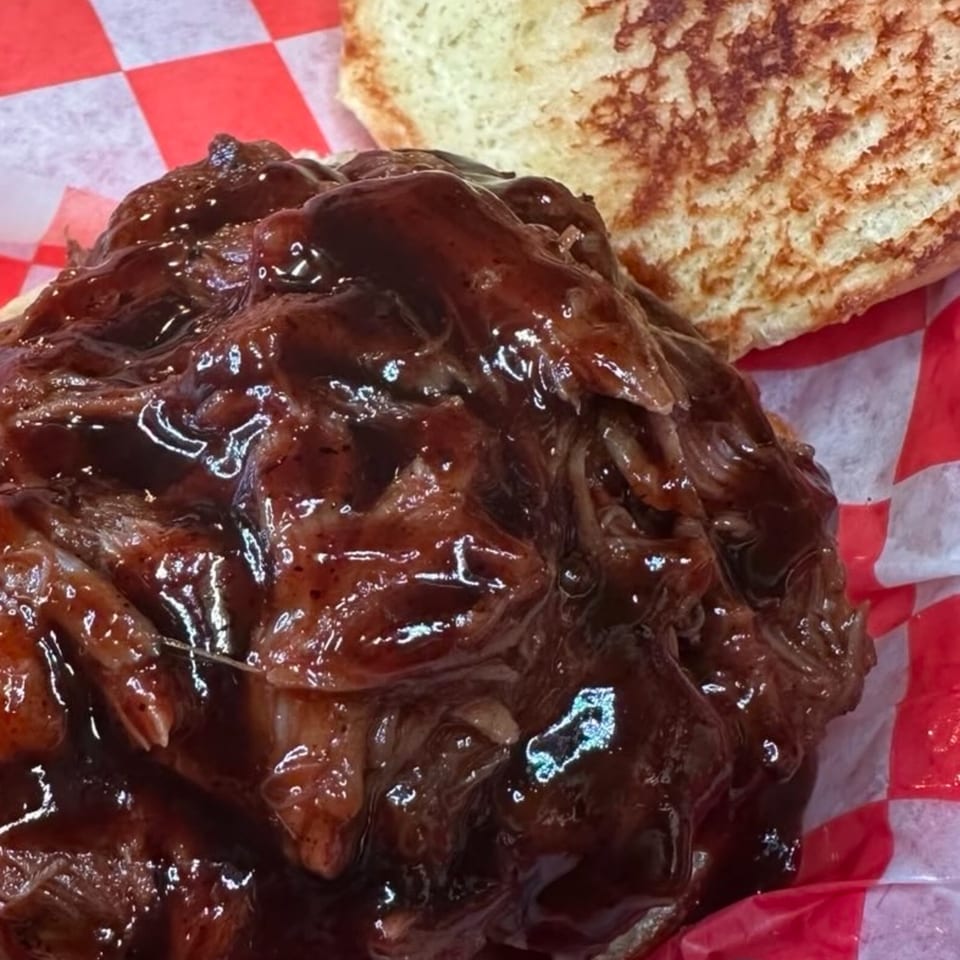 Close-up of a Horseshoe Bar & Grill pulled pork sandwich with barbecue sauce on a toasted bun.