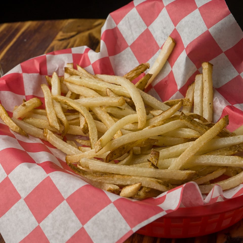 A red and white checkered basket overflowing with golden-brown french fries from The Horseshoe Bar & Grill.