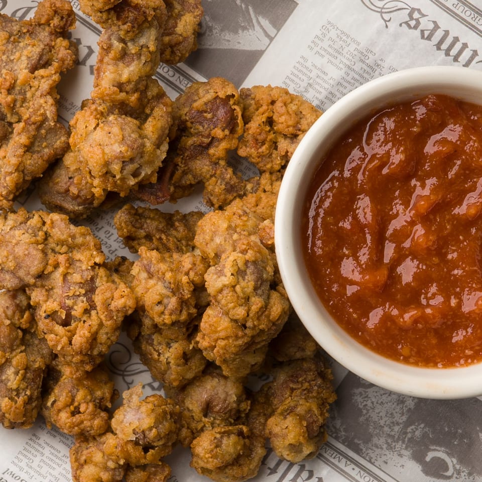 Crispy fried gizzards from The Horseshoe Bar & Grill, served with a side of red dipping sauce.